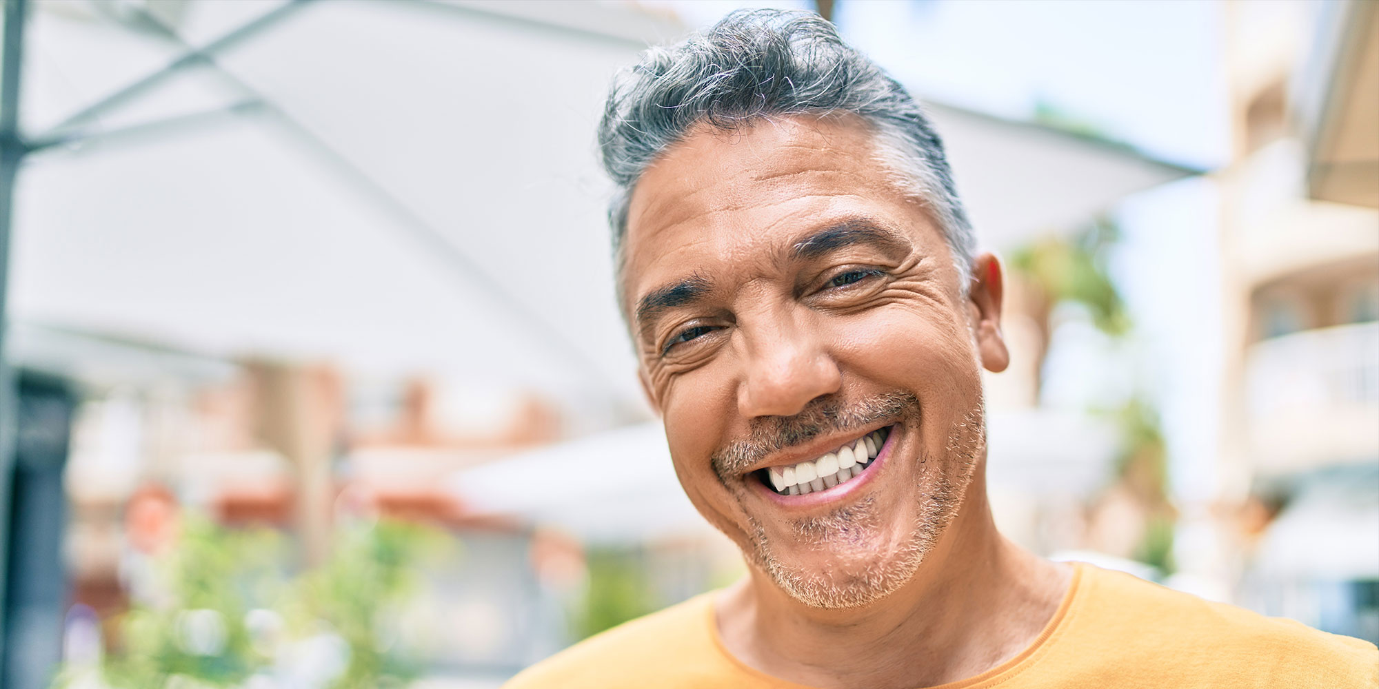 middle age person smiling brightly outside in the town area
